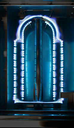 Grill burner ignited showing a blue and white arch design on a dark background