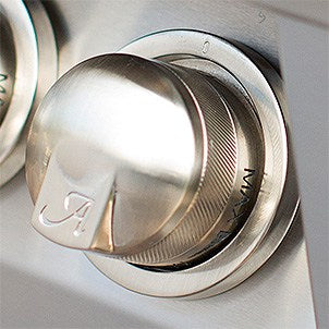 Close-up of a metallic knob with a brand logo on a metallic surface